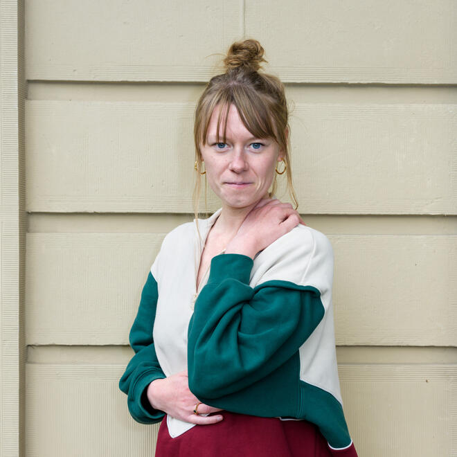 Foto van Corinne Heyrmann, een jonge blonde vrouw met een rode trui en een blauwe broek aan